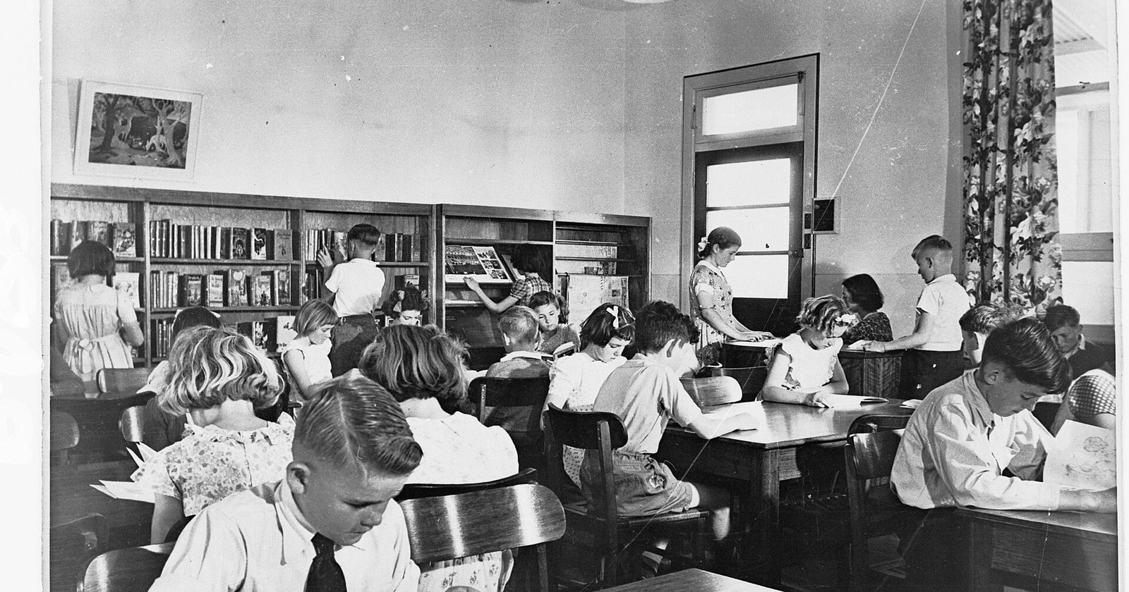 Dzieci czytające przy stołach w bibliotece szkolnej — obraz popołudnia, które rozwija zamiast przechowywać.